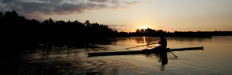 Sporter op het water bij zonsondergang, slecht zichtbaar zonder verlichting